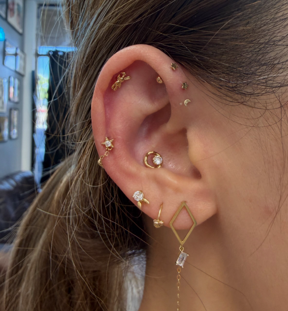 Multiple ear piercings with gold jewelry at Darkstar Tattoo Riverside CA