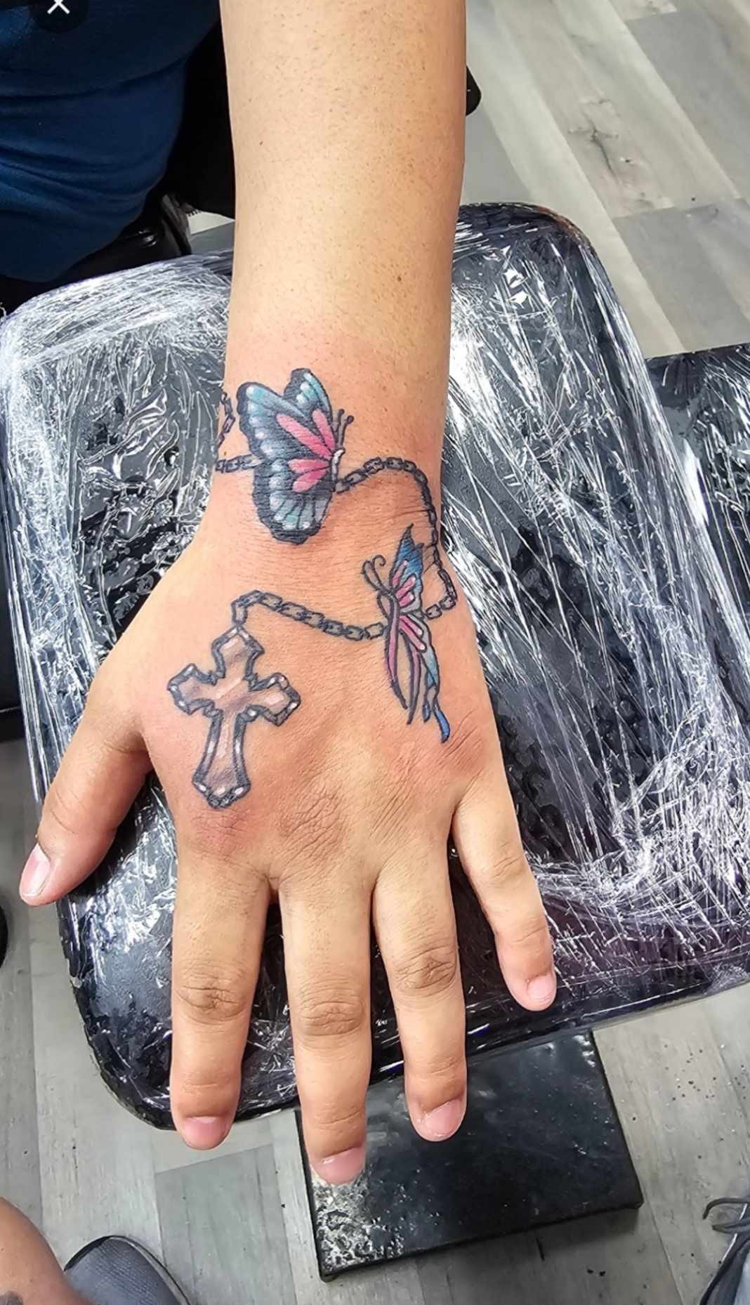 Color butterfly and cross hand tattoo at Darkstar Tattoo Riverside CA